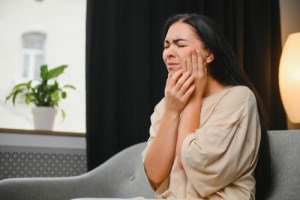 Woman holding cheek in severe pain